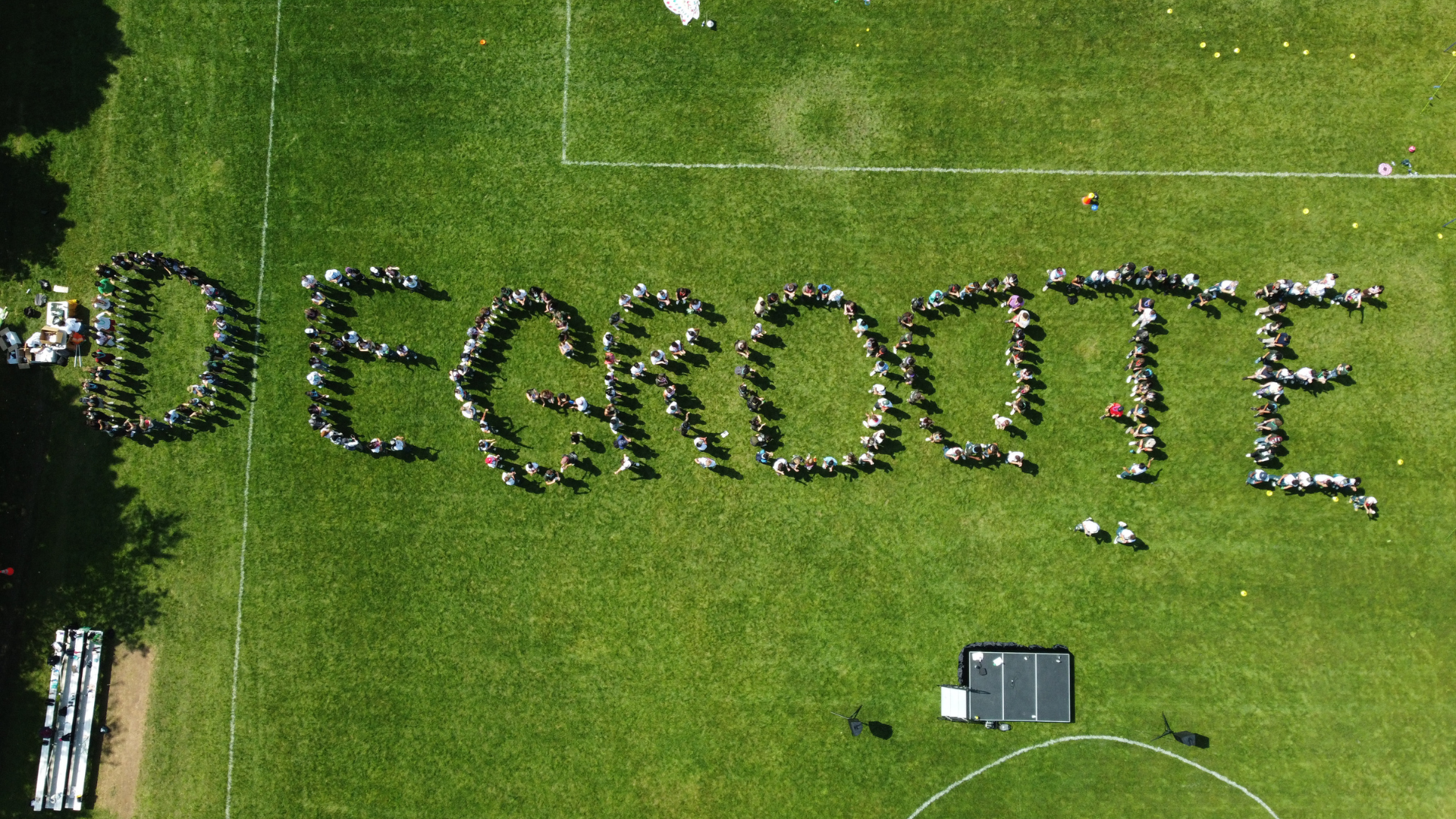 The grassy landscape reveals an artful arrangement of students forming the word 