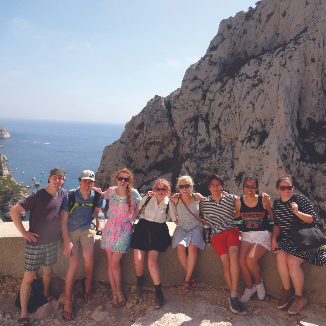 Undergraduate-Exchange. A cluster of people striking a pose for a photograph atop a cliff, showcasing a sense of unity and purpose while in exhange.
