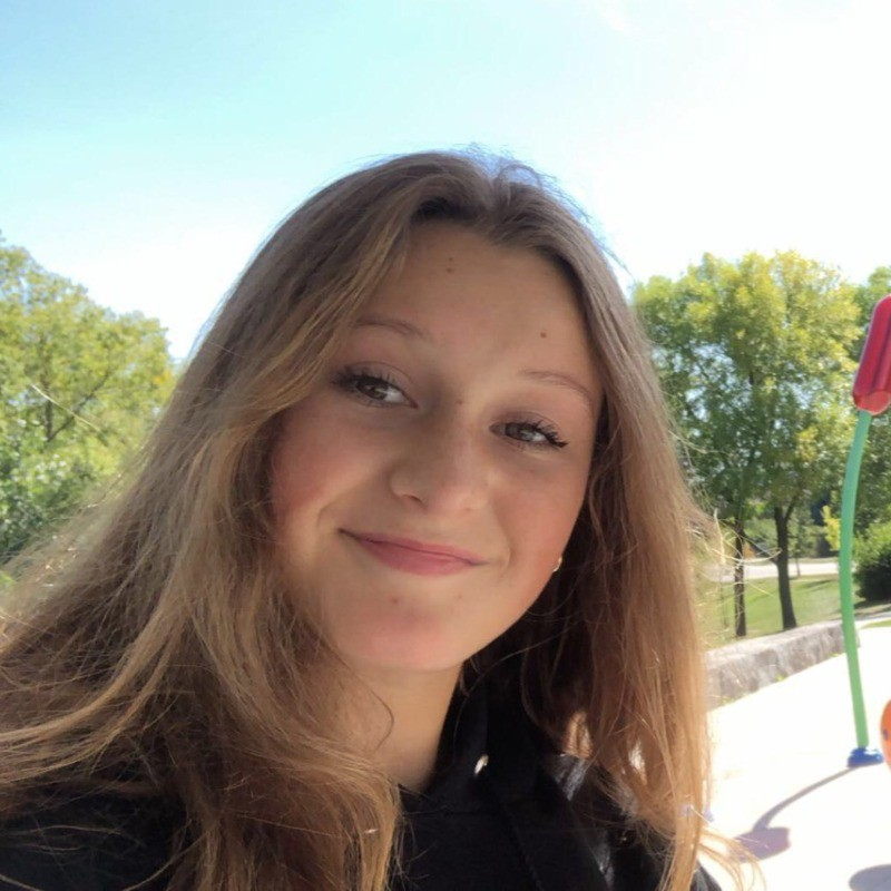 Portrait of Claire Lovely, a smiling woman with long, blond hair, in a dark sweater.